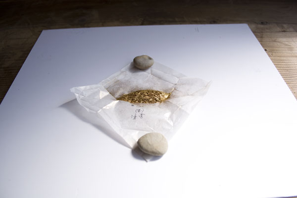 金継ぎの蒔絵で使う真鍮粉の包み紙を小石で押さえて広げる