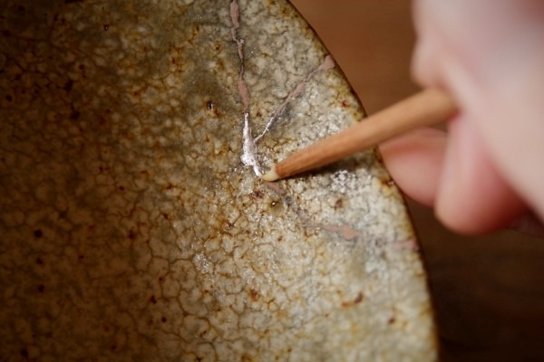 金継ぎの方法。蒔いた銀粉を鯛牙で磨いていく。