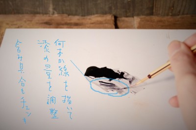 作業板の上で筆の中の漆の含み具合を調節する